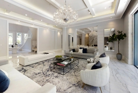 A living room with white furniture and a large rug.